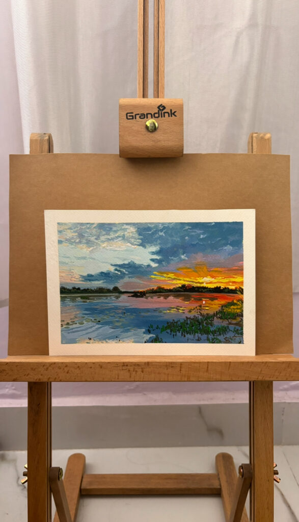 Vibrant sunset landscape painting with impasto texture displayed on a Grandink wooden easel, showcasing its use as an elegant display stand.